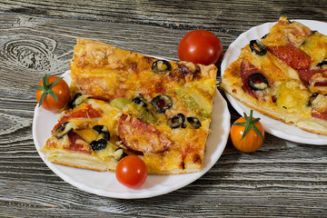 pizza with sausage, olives, tomatoes and cheese