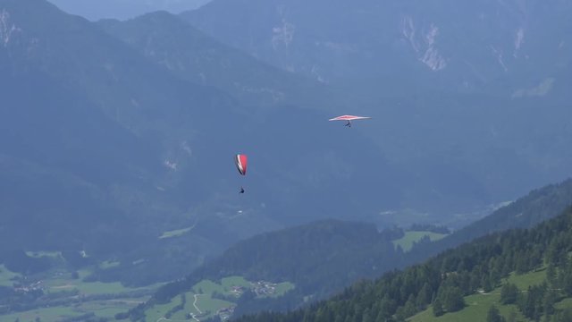 Red hang glider and red paraglider fly together