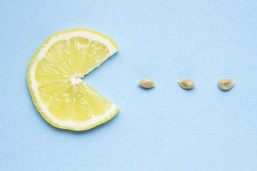 Yum-yum / Creative concept photo of a lemon slice eating seeds on blue background.
