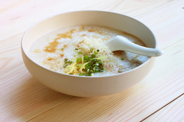 Congee, Rice porridge, Rice gruel, Rice soup, joke (China) on wooden table background, Top view, Selective and soft focus.