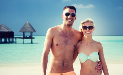 happy couple in swimwear hugging on summer beach