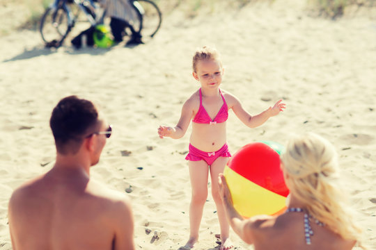 happy family playing with inflatable ball on beach