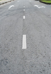 Asphalt road with arrow sign and white dot line