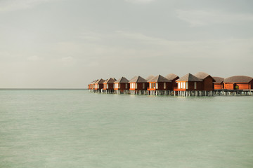 bungalow huts in sea water on exotic resort beach