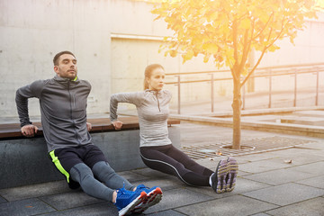 couple doing triceps dip on city street bench