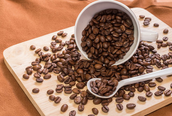 coffee beans on spoon and in cup with on wood