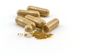 Herbal capsule and powder on white background.