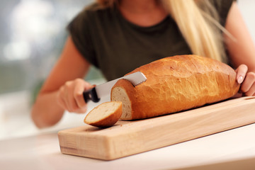 Naklejka premium Woman slicing loaf of bread