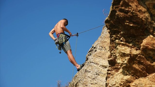 Climber Hanging On The Rock And Fastens With Hooks