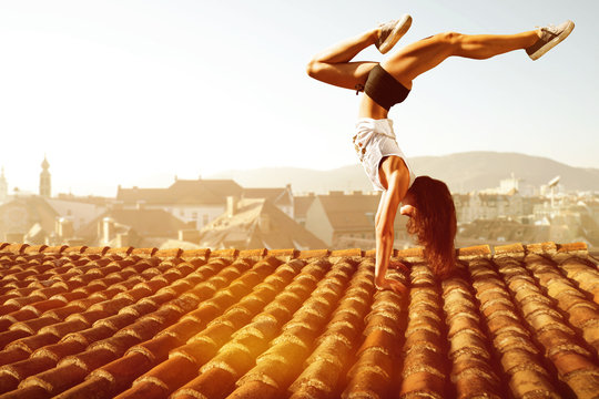 Frau macht einen Handstand auf Hausdach