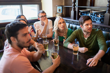 friends with beer watching football at bar or pub