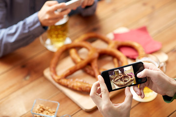 Naklejka na ściany i meble close up of hands picturing pretzel by smartphone