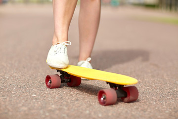 close up of female feet riding short skateboard