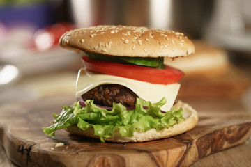 fun made fresh burger with marble beef, cheese and vegetables on olive board