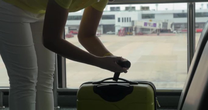 Woman using hand scales to weigh the suitcase by the widow at the airport