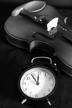 alarm clock & old classical violin on black fabric, bw filter " music & time to remember " concept