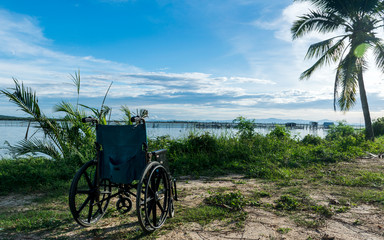 Fototapeta na wymiar Empty wheelchair on the lake at sunset.