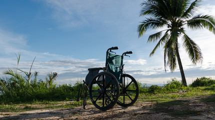 Obraz premium Empty wheelchair on the lake at sunset.