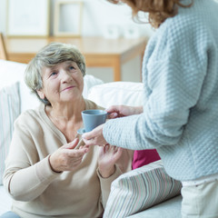 Caregiver giving elder woman coffee