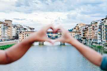 Loving couple making heart with their hands in front of Ponte Vecchio, Florence