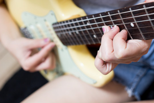 female teen musician playing electric guitar, focus to left hand