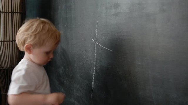 Little boy draw a chalk ona blackboard