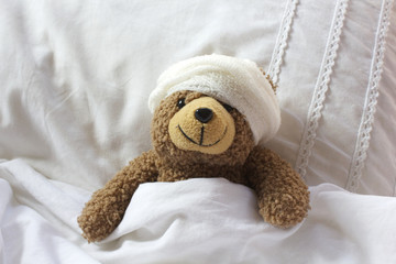 Teddy in bear bed with bandage on head
