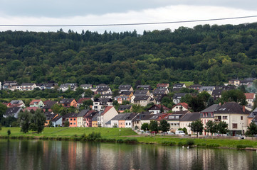 Fototapeta na wymiar River, houses, forest and sky. On the one side of the Moselle river is Germany (in the picture), on the other is Luxembourg.