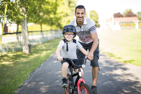 Father Teaching Son To Ride Bicycle