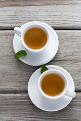 a couple of cups with tea and mint leaves. rustic weathered wood table, isolated, minimalist 