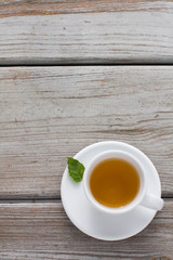 Mint tea  in a white cup and on a saucer, Rustic wood table, isolated, minimalist 