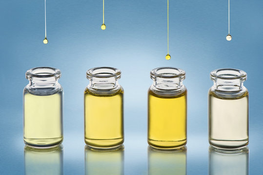 Four bottle with different cosmetics oil stand on the blue gradient metallic texture background