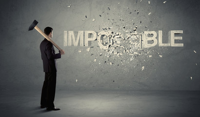 Business man hitting impossible sign with hammer