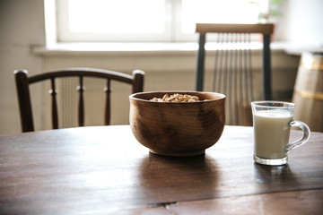 Wooden bowl and cup of milk with crackers on the table.