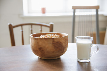 Wooden bowl and cup of milk with crackers on the table.