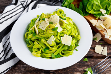 Tagliatelle pasta with spinach, avocado and parmigiano cheese, herbs in white plate. concept of healthy food
