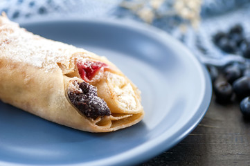 closeup pancake with berries on blue flat on dark wooden background