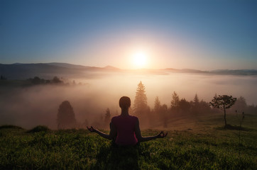 young woman doing yoga fitness in nature with ountain view on sunset