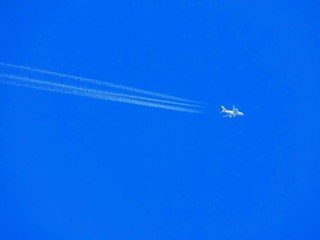 Airplane with chemtrails on blue sky