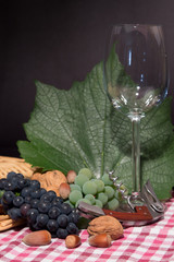 One wine glass and green leaves of the grape on black background. Close up