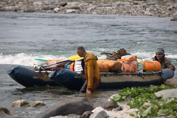 Two men pulled the catamaran up the rapids. Small Usa river, Polar Urals.