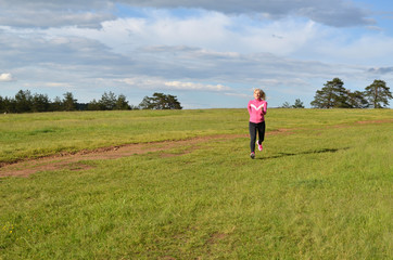 Naklejka na ściany i meble Woman in sportswear running on a field in spring