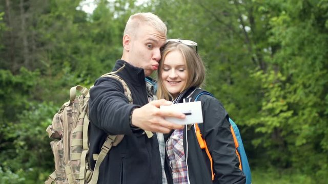 Happy kissing in the forest and doing photos on smartphone

