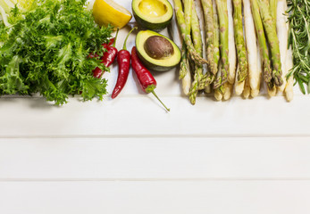 Asparagus, avocado and lettuce on a white wooden background