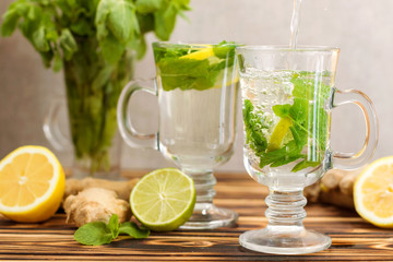 Healthy ginger tea with lemon, lime and mint on table close-up. Healthy drink. Autumn, winter beverage concept.