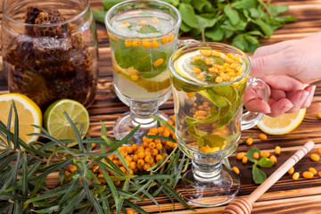 Cup of tea with sea ​​buckthorn, lemon, lime, honey and mint. Autumn, winter beverage concept.