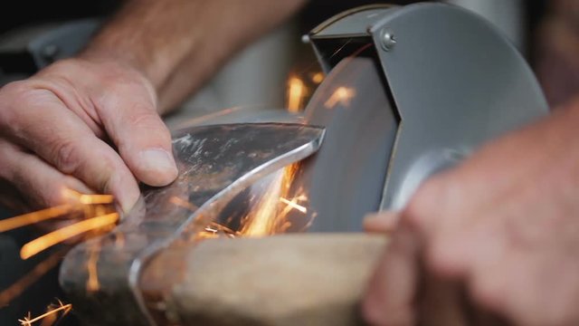 The man sharpens ax on a special machine. Old ax.