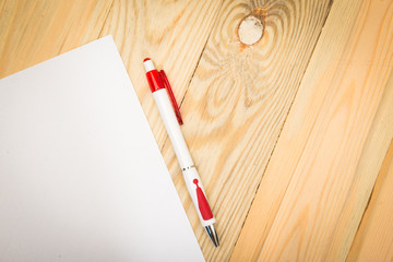 Obraz premium Blank white paper with pen on a wooden desk.
