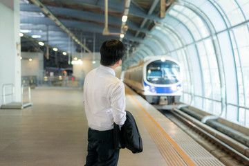 Asian young businessman waiting metro train at train station. 