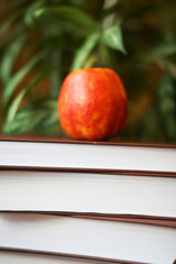 Stack of books on wooden table for reading with red delicious ap